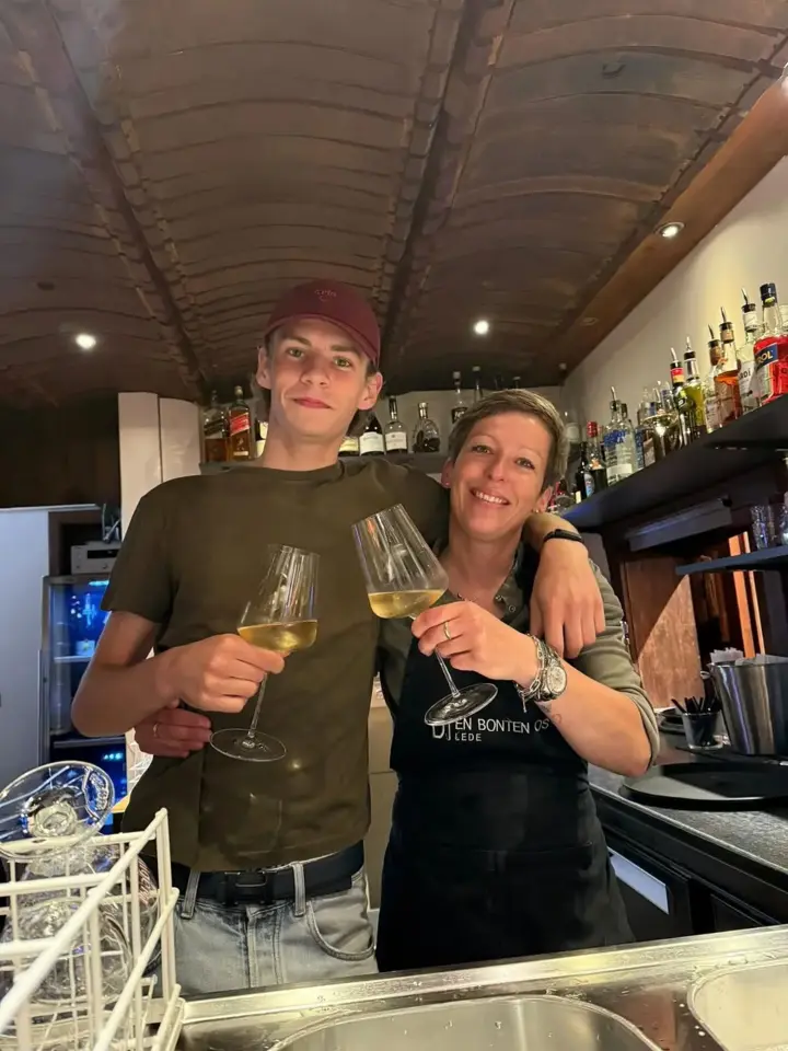 Het team klinkt met een glas wijn aan de bar